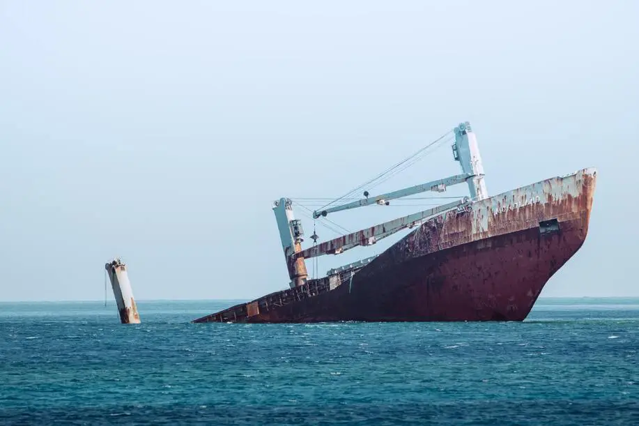Parte del casco oxidado de un carguero abandonado y parcialmente hundido en el mar